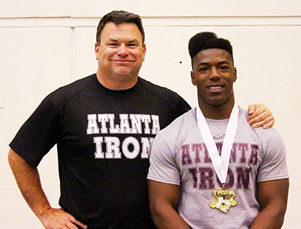 Atlanta Iron Head Coach Craig Fant stands beside Alvin Battle after the senior lifter wrapped up Atlanta’s first-ever individual powerlifting state championship. Alvin won the gold medal after lifting 1,465 pounds at the State Meet. With that total Alvin beat out the silver medalist by 20 pounds.